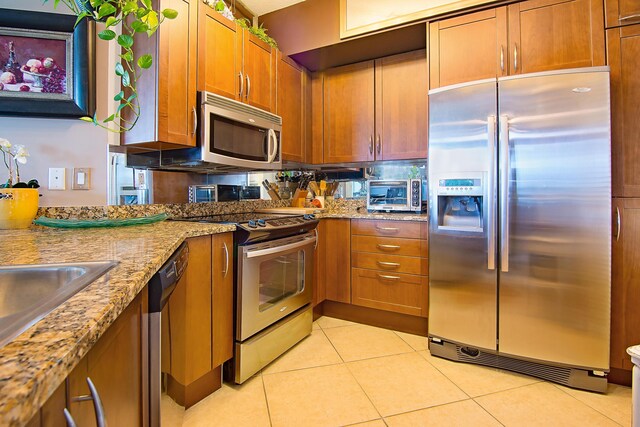 kitchen featuring appliances with stainless steel finishes, light stone countertops, and light tile patterned floors