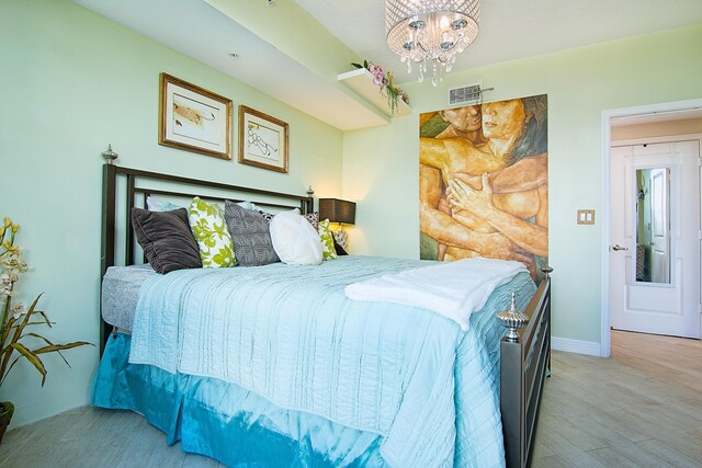 bedroom featuring wood-type flooring and an inviting chandelier