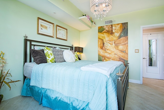 bedroom with a chandelier, light wood finished floors, visible vents, and baseboards