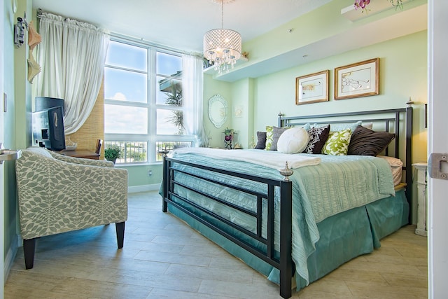 bedroom featuring baseboards, light wood-type flooring, and a notable chandelier