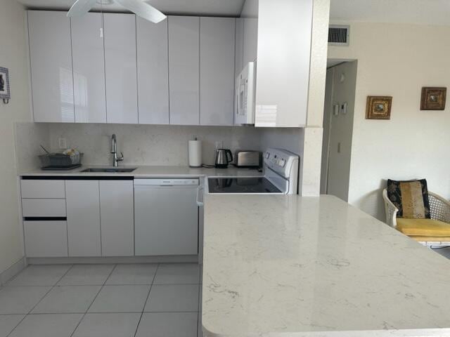 kitchen featuring backsplash, white cabinetry, sink, white appliances, and light tile patterned flooring