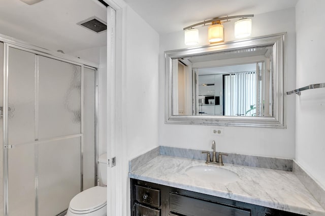 bathroom featuring toilet, a shower stall, and vanity