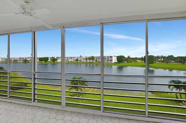 unfurnished sunroom featuring a water view, ceiling fan, and a healthy amount of sunlight