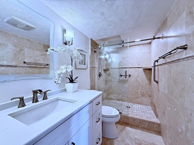 bathroom featuring a tile shower, vanity, toilet, and a textured ceiling