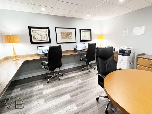 office area with built in desk, a drop ceiling, and light hardwood / wood-style floors