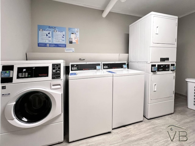 clothes washing area featuring stacked washer / dryer, light wood-type flooring, and washer and clothes dryer