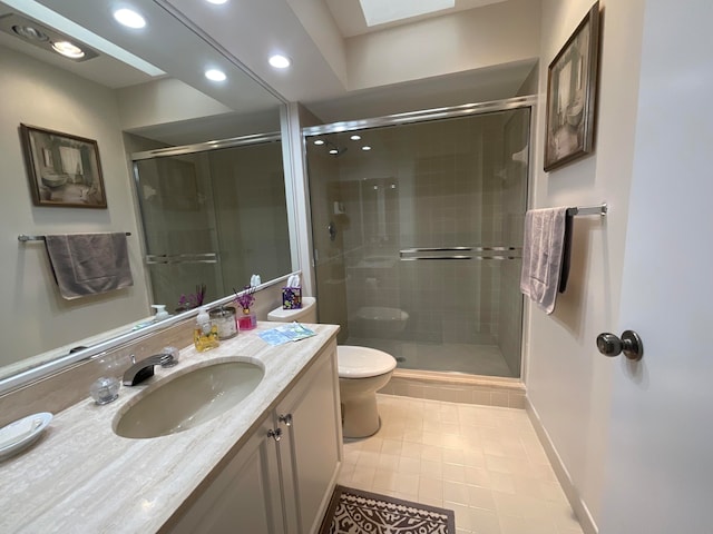 bathroom featuring a skylight, a shower with shower door, toilet, vanity, and tile patterned flooring