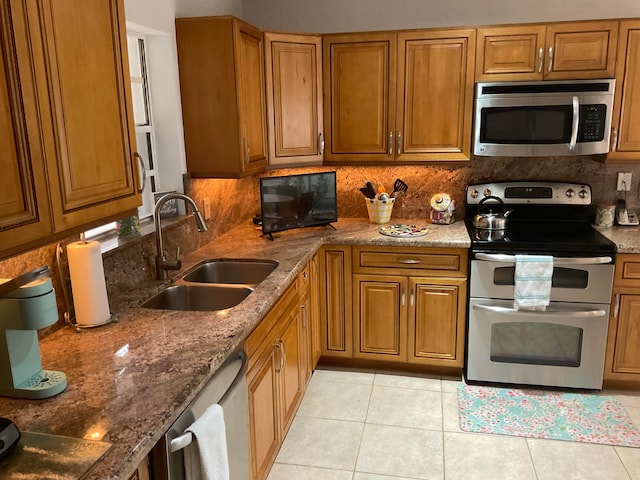 kitchen featuring tasteful backsplash, light tile patterned floors, stone countertops, sink, and stainless steel appliances