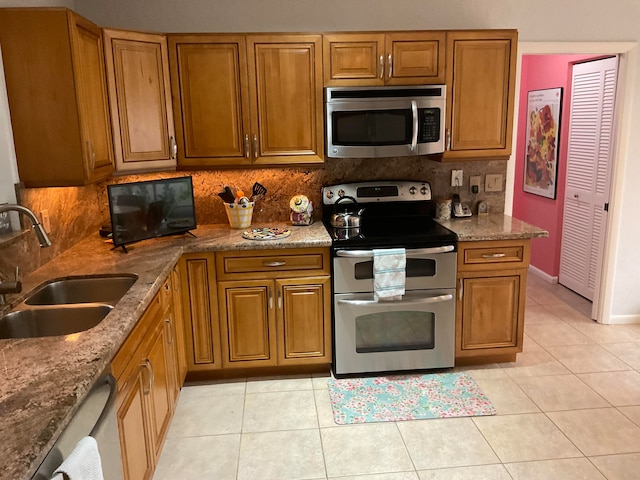 kitchen with sink, appliances with stainless steel finishes, decorative backsplash, and light tile patterned floors