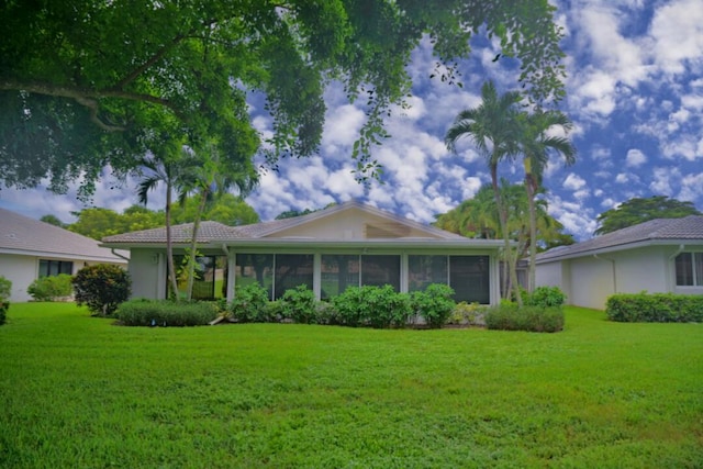 ranch-style home featuring a sunroom and a front lawn