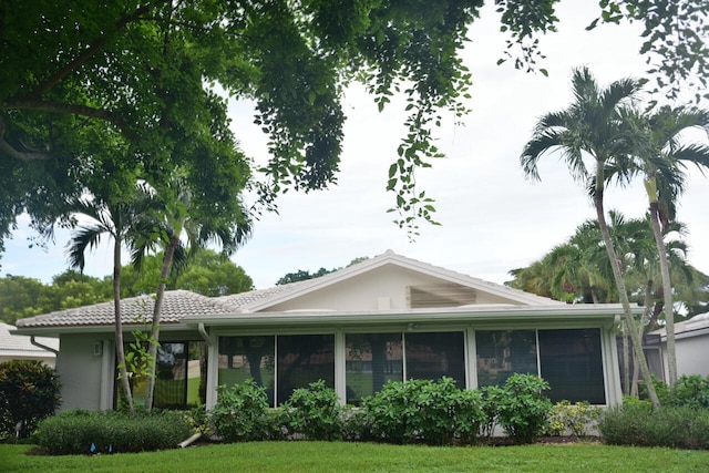 view of front of home featuring a sunroom and a front lawn