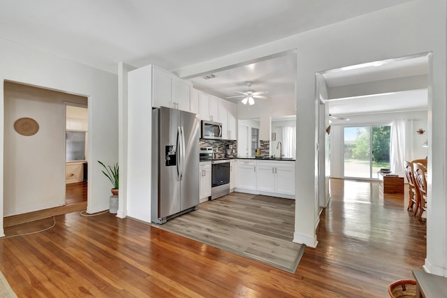 kitchen with hardwood / wood-style floors, appliances with stainless steel finishes, sink, and ceiling fan