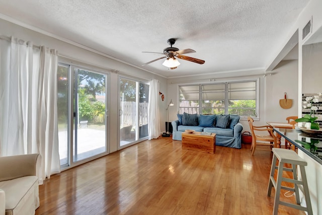 living room with hardwood / wood-style floors, ceiling fan, and a textured ceiling