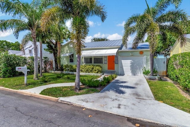 view of front of home featuring metal roof, an attached garage, concrete driveway, a front lawn, and a standing seam roof