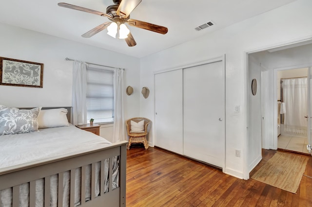 bedroom with ceiling fan, visible vents, baseboards, a closet, and wood-type flooring