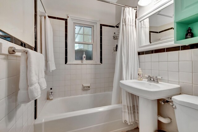 full bathroom featuring sink, shower / tub combo with curtain, decorative backsplash, tile walls, and toilet