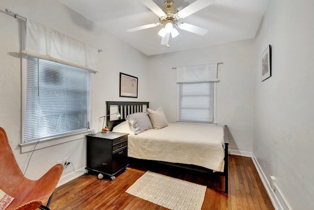 bedroom with ceiling fan, wood-type flooring, and baseboards