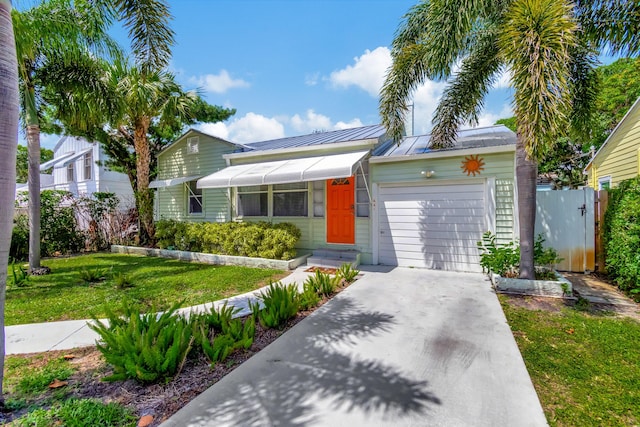 single story home featuring concrete driveway, an attached garage, a standing seam roof, metal roof, and a front lawn