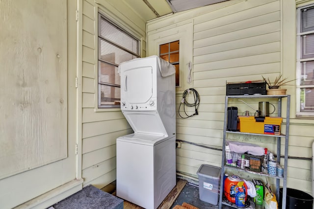 laundry area with stacked washer / drying machine and wood walls