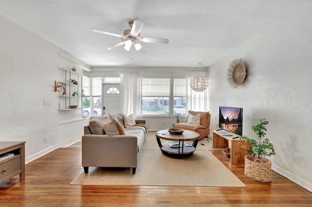 living room with ceiling fan, baseboards, and wood finished floors