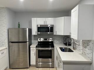 kitchen with white cabinets, decorative backsplash, sink, and appliances with stainless steel finishes