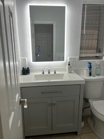 bathroom featuring toilet, decorative backsplash, and vanity