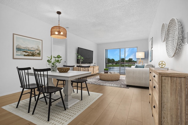 dining space featuring a textured ceiling and light hardwood / wood-style flooring