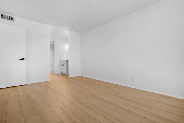 unfurnished room featuring light wood-type flooring and a textured ceiling