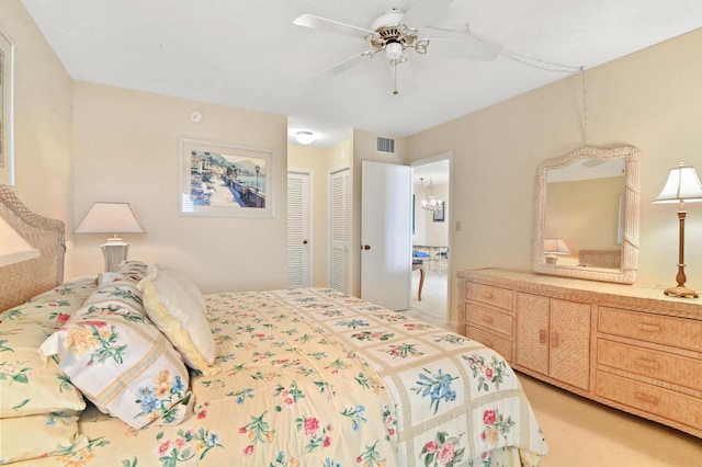 carpeted bedroom with ceiling fan with notable chandelier and a closet