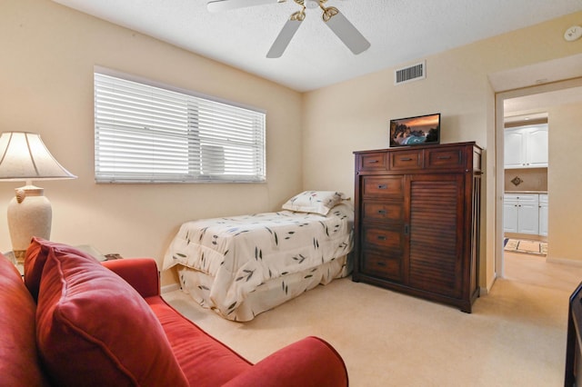 bedroom with ceiling fan, light carpet, and a textured ceiling