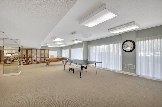 rec room featuring light colored carpet and a textured ceiling