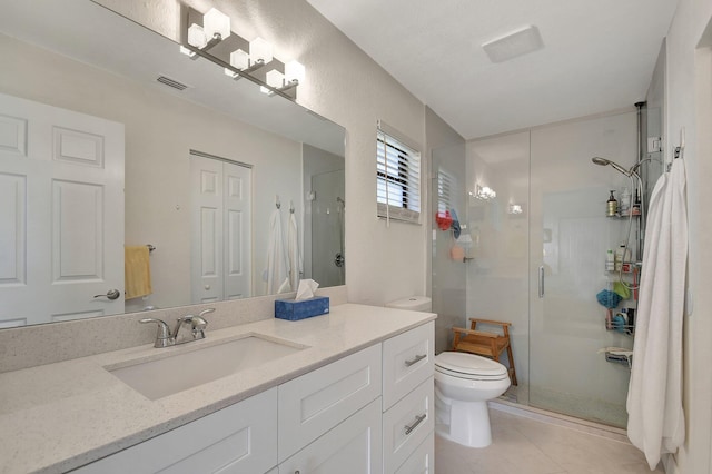 bathroom featuring toilet, vanity, tile patterned floors, and a shower with door