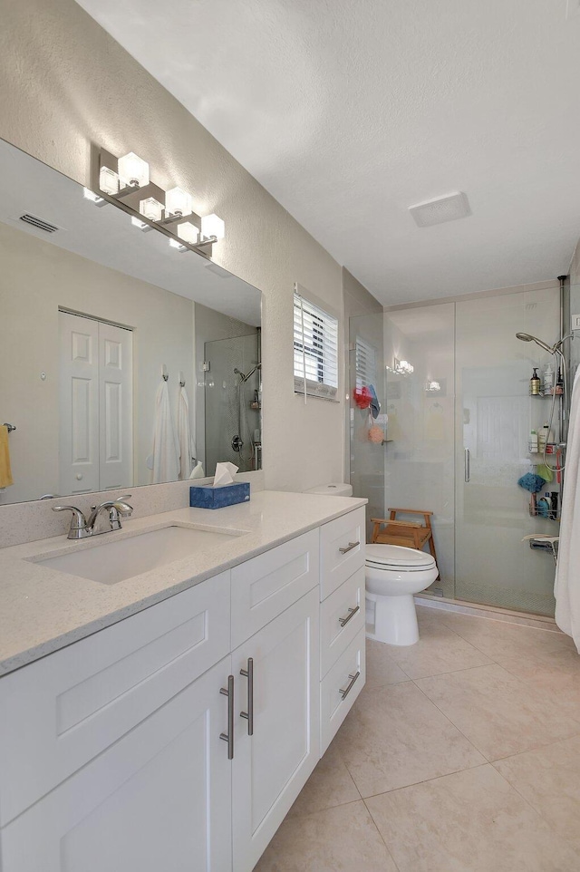 bathroom with a textured ceiling, toilet, tile patterned floors, walk in shower, and vanity