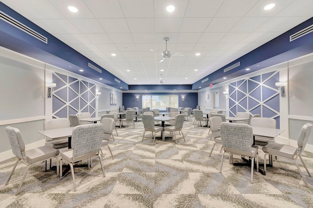 carpeted dining room featuring a drop ceiling and ceiling fan