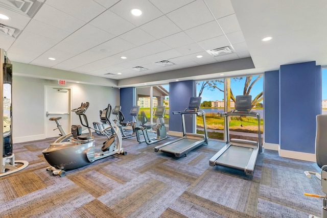 exercise room with a paneled ceiling and carpet