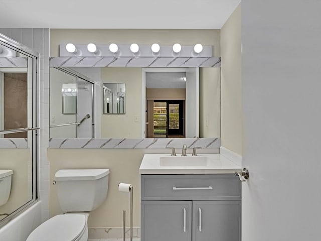 full bathroom featuring toilet, vanity, and shower / bath combination with glass door