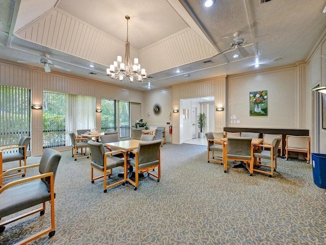 dining area featuring carpet floors, ceiling fan with notable chandelier, and a tray ceiling