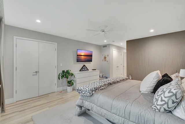 bedroom featuring ceiling fan, two closets, and light hardwood / wood-style floors