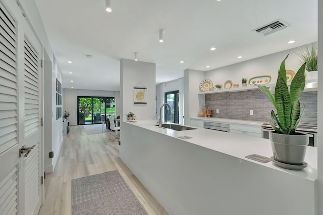 kitchen featuring recessed lighting, a sink, visible vents, light countertops, and light wood finished floors