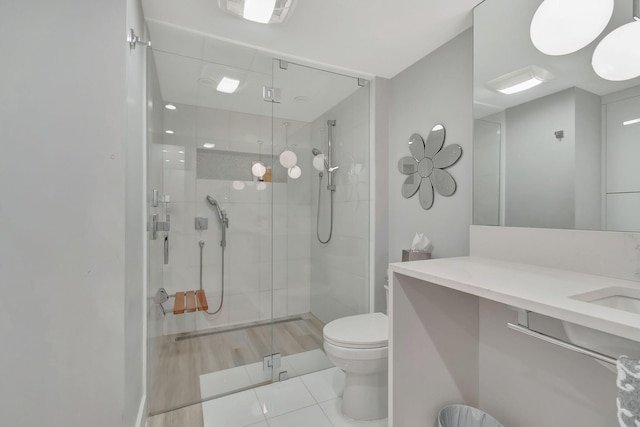 bathroom with walk in shower, vanity, hardwood / wood-style floors, and toilet