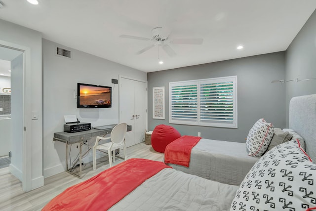 bedroom with light wood-type flooring, ceiling fan, and a closet