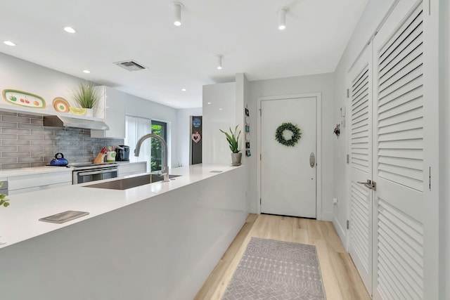 interior space featuring a sink, visible vents, white cabinetry, light wood-style floors, and light countertops