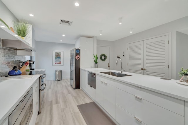 kitchen featuring light hardwood / wood-style flooring, stainless steel appliances, sink, and white cabinetry