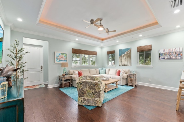 living room featuring dark wood-type flooring, a tray ceiling, crown molding, and ceiling fan