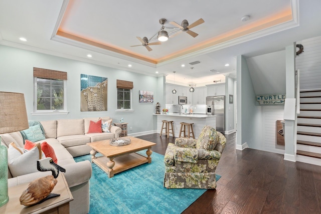 living room featuring ceiling fan, dark hardwood / wood-style floors, a raised ceiling, and sink