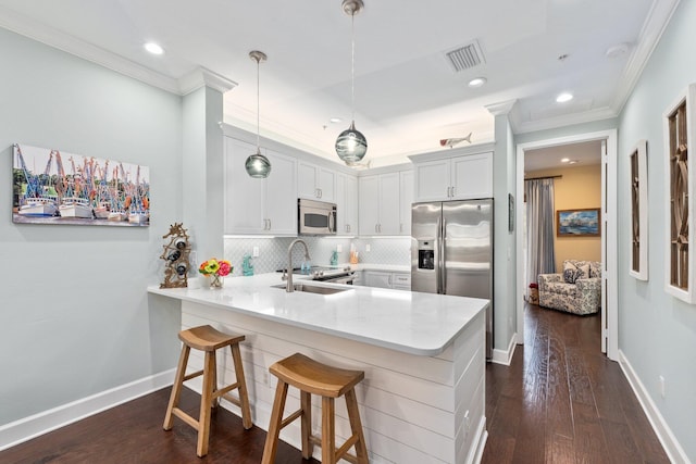 kitchen with decorative light fixtures, appliances with stainless steel finishes, kitchen peninsula, dark wood-type flooring, and a breakfast bar area