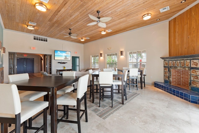 dining room featuring ceiling fan, a fireplace, and wooden ceiling