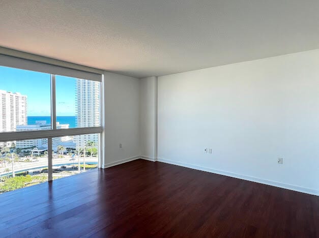 spare room featuring a water view, floor to ceiling windows, hardwood / wood-style floors, and a textured ceiling