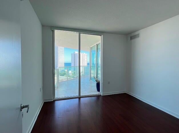 unfurnished room with wood-type flooring and a textured ceiling