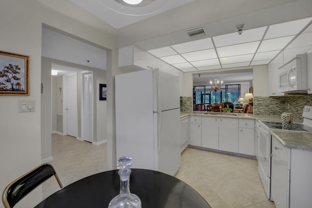 kitchen with light tile patterned flooring, an inviting chandelier, decorative backsplash, white appliances, and white cabinets